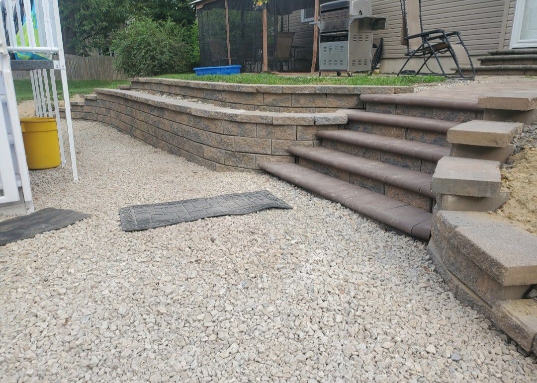 Stacked block retaining wall with built-in steps above a gravel landscape path
