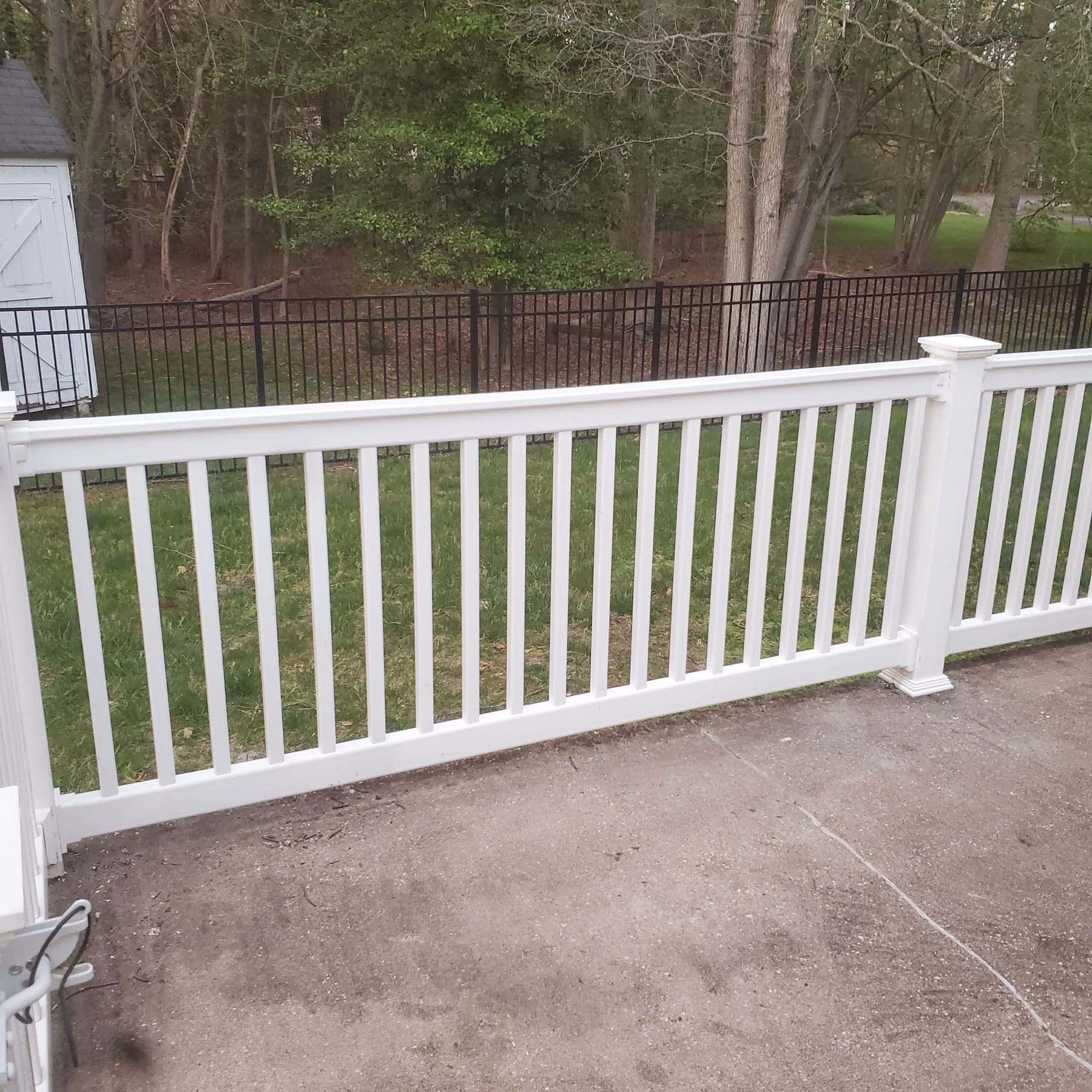 White vinyl railing installed along the edge of a concrete patio